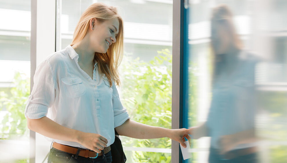 Kobieta otwiera drzwi za pomocą karty kontroli dostępu